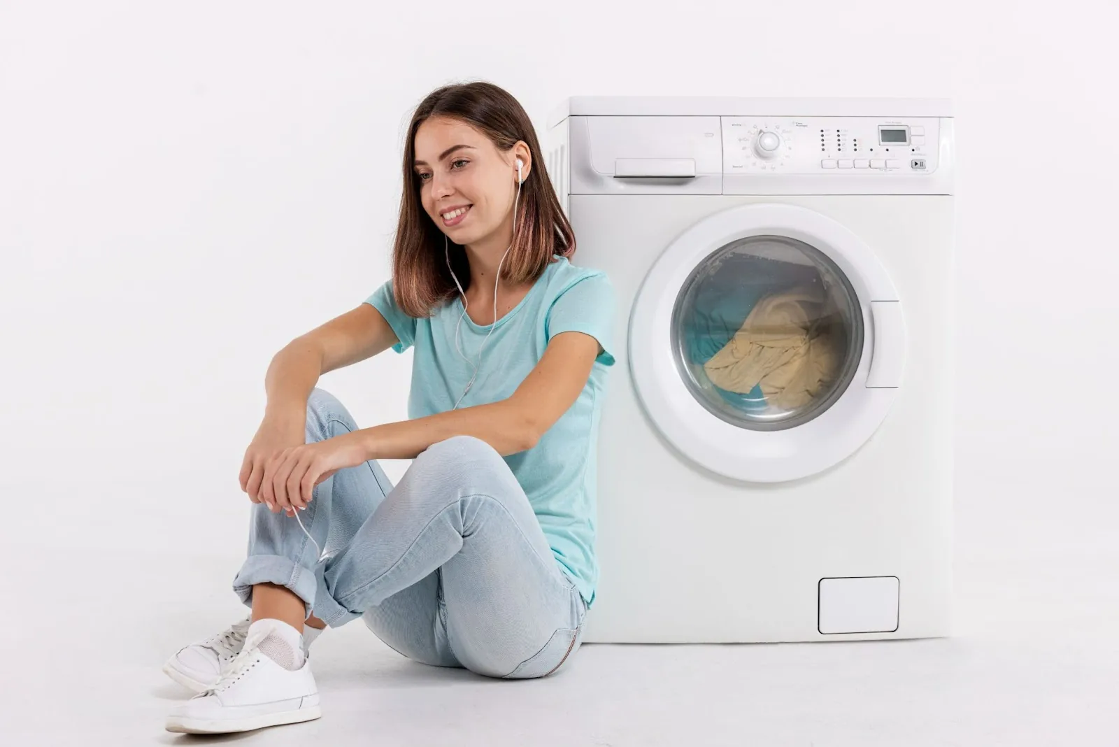 Woman sitting by the washing machine as she does her laundry