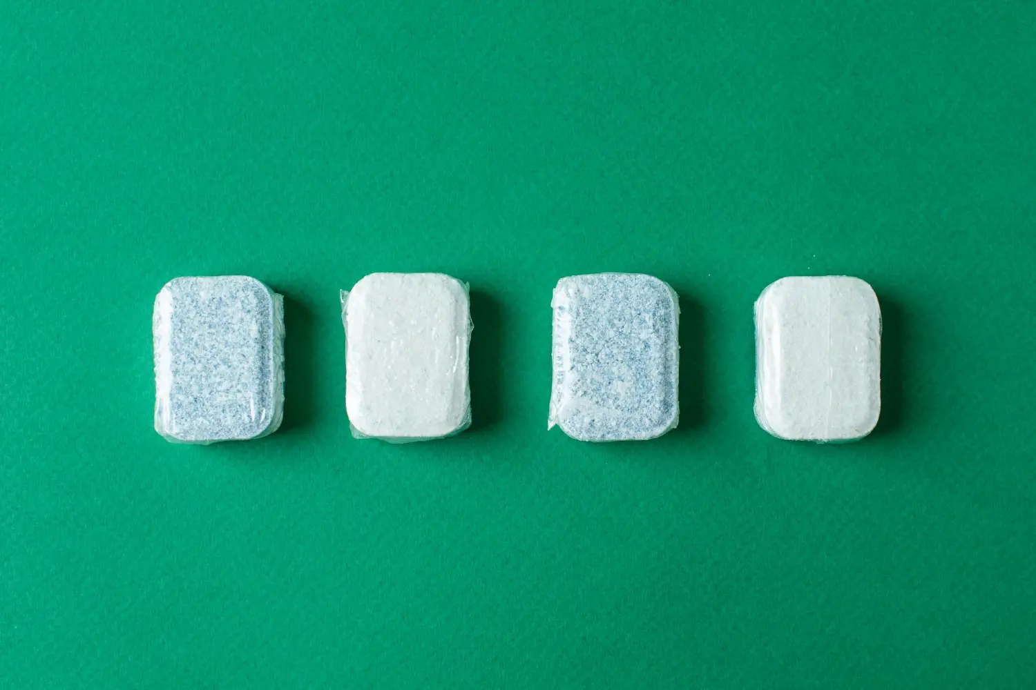 Washing machine cleaning tablets close up image on a green background
