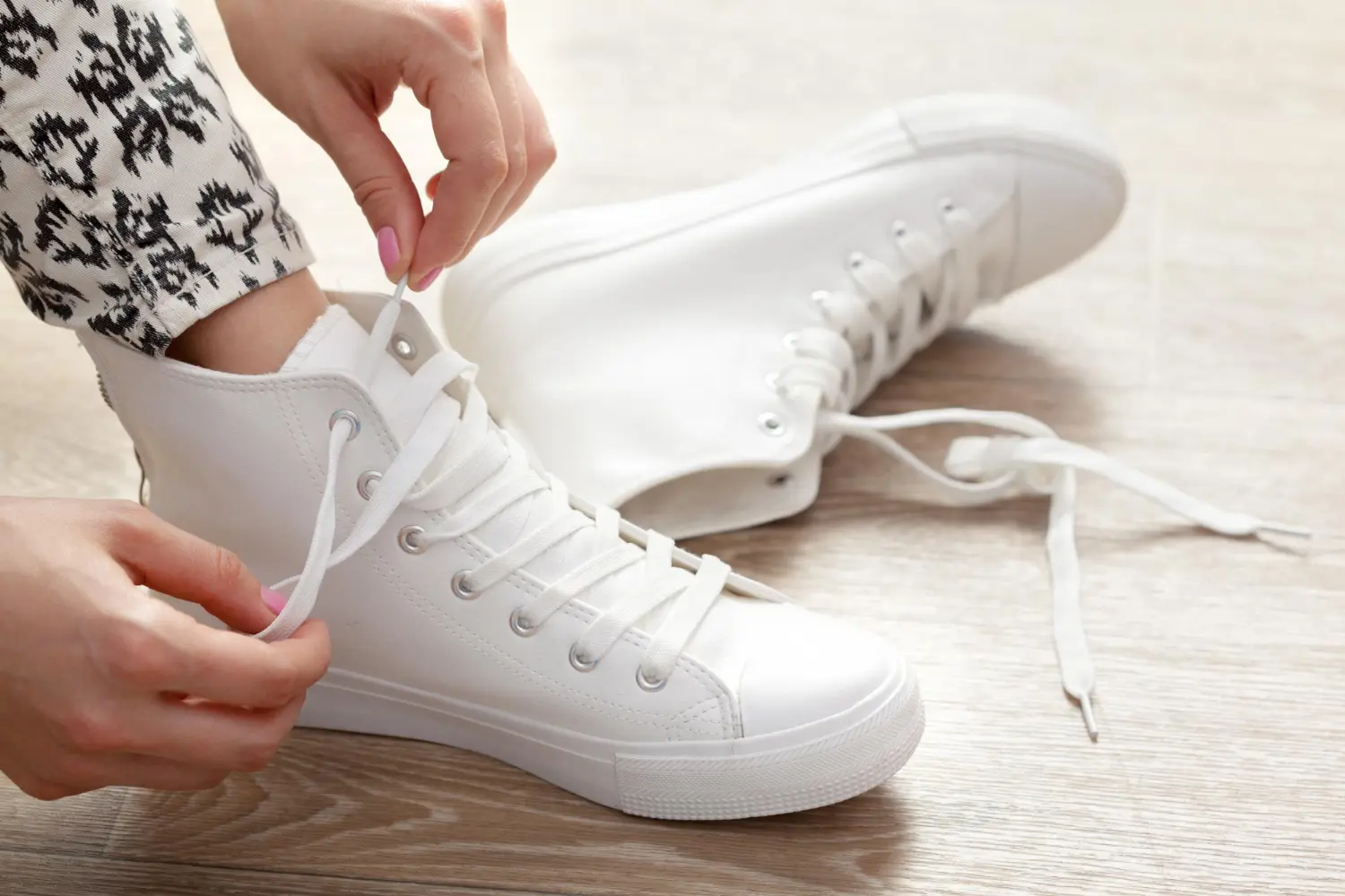A gorgeous lady tying her white shoe laces.