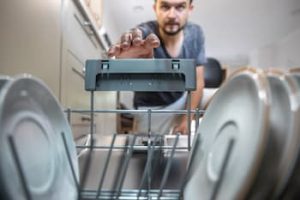 man-front-open-dishwasher-takes-out-clean-dishes-after-washing (1)